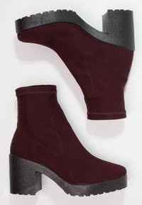 Weinrote Knöchelstiefel mit einem strukturierten Obermaterial, elastischen Seitenpanelen und klobigem schwarzen Plateau-Absatz mit gerippter Sohle.