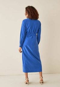 Langarmige, blauwe jurk met een ceintuur, een kraag en knoopmanchetten. Soepele stof en een enkellange ontwerp met een rechte snit.