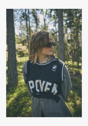 Black mesh basketball jersey with "PROVEN" in large white letters, paired with a checkered button-up shirt. Accessories include sunglasses and a bead necklace.