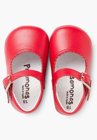 Zapatos Mary Jane de cuero rojo con bordes ondulados, correa con hebilla y acabado liso. El interior presenta el nombre de la marca impreso y la talla.
