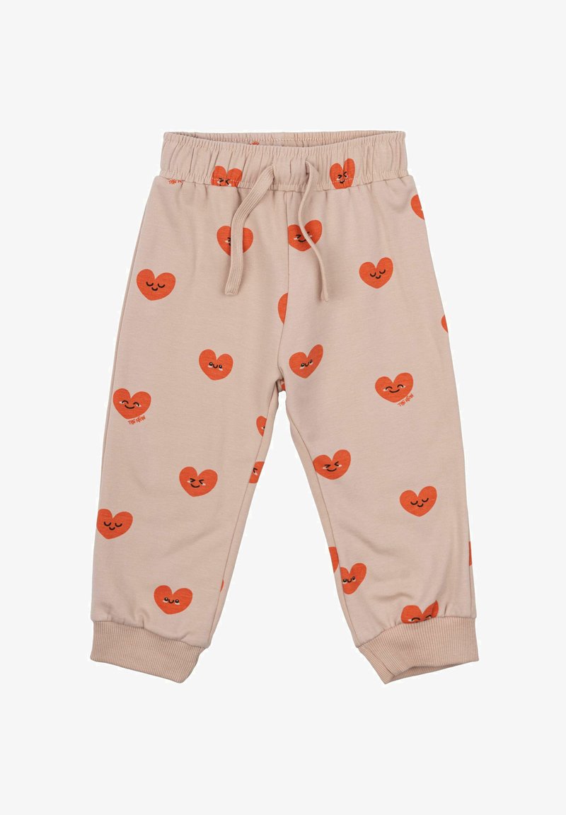 Bēšas jogger bikses ar elastīgu jostasvietu, kurām ir atkārtoti oranži sirdītes raksti ar smaidīgām sejām. Mīksts audums un stūra apakšdaļas.