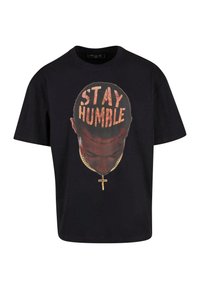 Fekete pamut póló, amelyen egy fej grafika látható "STAY HUMBLE" felirattal, arany lánccal és kereszttel. Laza szabás, rövid ujjak.