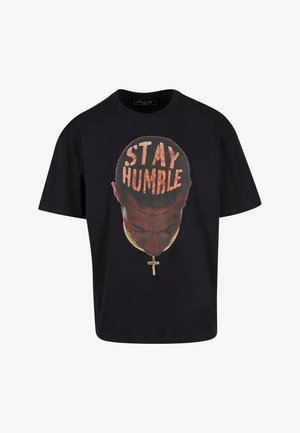 Black cotton t-shirt featuring a graphic of a head with "STAY HUMBLE" text, gold chain, and cross. Casual fit with short sleeves.