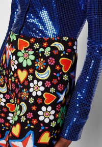 Leotard colorido y estampado en negro, con flores, corazones y estrellas. Combinado con una blusa azul de lentejuelas con una textura brillante.