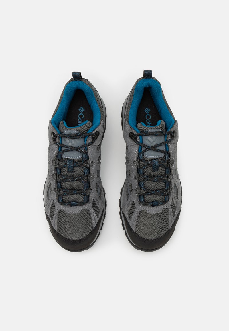 Grijze wandelschoenen hebben een bovenwerk van mesh, een zwarte rubberen neuskap, blauwe accenten en gestructureerde veters voor een veilige pasvorm en duurzaamheid.