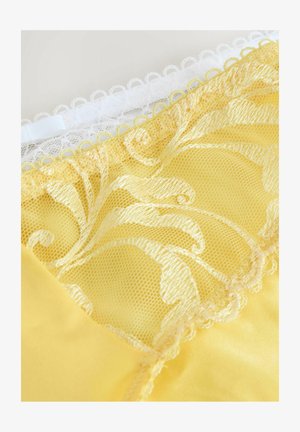 Lingerie gialla con dettagli in pizzo. Presenta una morbida texture di raso e un intricato motivo in pizzo floreale nella parte superiore, accentuato da un bordo bianco.