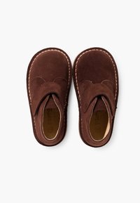 Zapatos de ante marrón con punta redonda y una costura, que presentan una textura de tela suave y un diseño de solapa superpuesta.