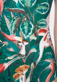 Geprinte jurk met levendige groene bladeren, roze vogels en paddenstoelen. Vloeiende stof met gedetailleerde illustraties in meerdere kleuren.