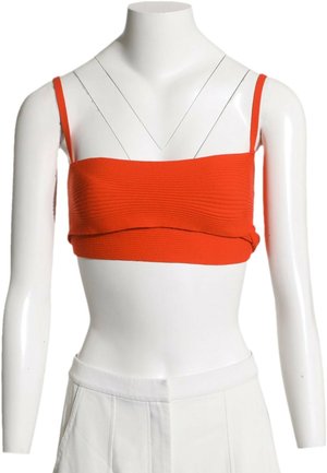 Débardeur court rouge côtelé avec fines bretelles sur buste de mannequin blanc portant un pantalon blanc.