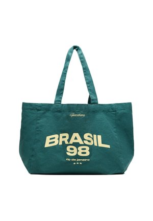 Zöld táska két füllel, sárga felirat: "Copacabana BRASIL 98 rio de janeiro", alatta három kis csillag.