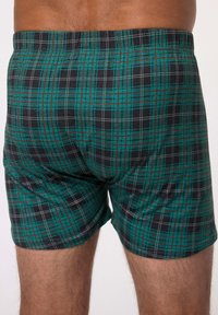 Paitatorsoer, jotka esittävät vihreä-mustaa ruutukuvioita, joissa on valkoisia ja punaisia yksityiskohtia, valmistettu pehmeästä kankaasta ja elastisella vyötärönaualla.