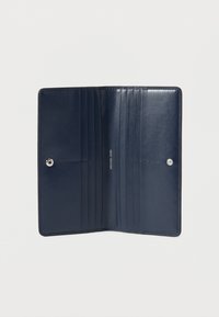 Εσωτερικό πορτοφολιού από ναυτικό μπλε δέρμα με πολλαπλές θήκες για κάρτες, απαλή υφή και κούμπωμα με κλιπ σε ασημένιο χρώμα.