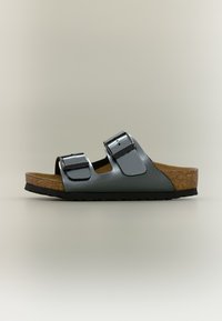 Πέδιλο ανοιχτού δακτύλου με δύο μαύρες ρυθμιζόμενες λουρίδες με αγκράφες και πάτο από φελλό με μαύρη λαστιχένια σόλα, εμφανίζεται σε προφίλ σε ουδέτερο φόντο.