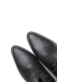 Black leather shoes with pointed toes, smooth texture, and minimalistic design. Features simple stitching and a lace-up closure.