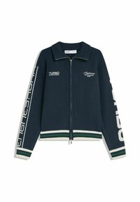 Sweat à fermeture éclair navy avec col côtelé, poignets et ourlet rayés blanc et vert, et impressions de texte blanc sur la poitrine et les manches.