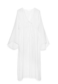 Hvid, flydende kjole med dyb V-hals, bånd foran og brede klokkeslætærmer. Har en samlet talje og let, tekstureret stof.