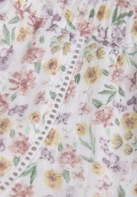 Vit tyg med blommönster i mjuka pastellfärger, inklusive rosa, gult och lila blommor. Delikat spetskant längs kanten.