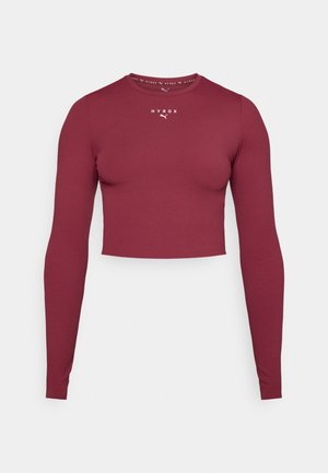 Burgunderfarbener langärmeliger Crop-Top aus glattem, elastischem Stoff. Mit rundem Ausschnitt und kleinem weißen Logo auf der Brust.