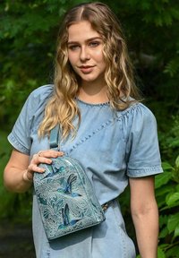 Türkiser Rucksack mit floralem Design, geprägten Vögeln und glänzender Oberfläche. Verfügt über einen einzigen Schultergurt und eine abgerundete Oberseite.