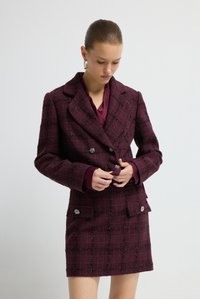 Blazer doppiopetto in tweed color bordeaux con motivo a quadri, caratterizzato da bottoni metallici, colletto con revers incernierati e silhouette aderente.