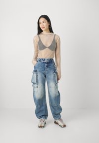 Langermet topp i mesh, svart-hvitt rutet bustier under, kombinert med lyseblå cargo-jeans med flere lommer.