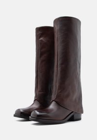 Καφέ δερμάτινες μπότες μέχρι το γόνατο με λεία υφή, στρογγυλή μύτη και τετράγωνο τακούνι; διαθέτουν ελαφρώς φαρδύ σχέδιο στην επάνω πλευρά.
