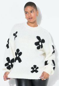 Übergroßer weißer Pullover aus flauschigem Strickstoff mit schwarzen Blumenmustern, geripptem Ausschnitt und Bündchen. Lässiges, gemütliches Design.