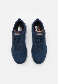 Marineblå nät sneakers med texturerad överdel, lättvikt design, snörning och kontrasterande orange detaljer på tungan och logotypen.