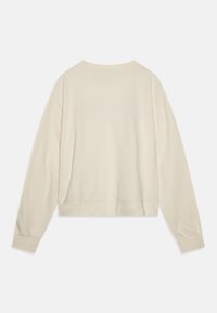 Jasnobeżowy krótki sweater z długimi rękawami, prążkowanym dekoltem i mankietami, o gładkiej fakturze materiału. Brak widocznych wzorów lub elementów metalowych.