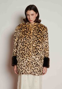 Casaco de pelo sintético com estampado de leopardo, gola redonda, fecho de botões e detalhes de pelo escuro nos punhos. Textura macia e corte descontraído.