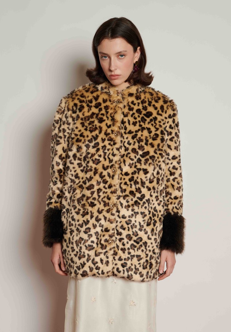 Casaco de pelo sintético com estampado de leopardo, gola redonda, fecho de botões e detalhes de pelo escuro nos punhos. Textura macia e corte descontraído.