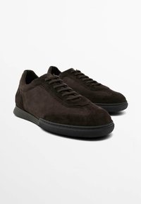 Mörkbruna mockasneakers med slät textur, utrustade med snörning, kontrasterande gummisula och rundad tå.