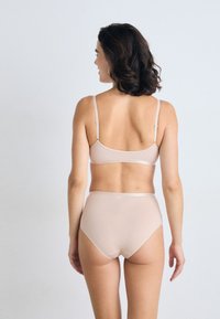 Beige bh og høyhofte truse-sett, med jevnt stoff, justerbare stropper og en sømløs design for komfort og passform.