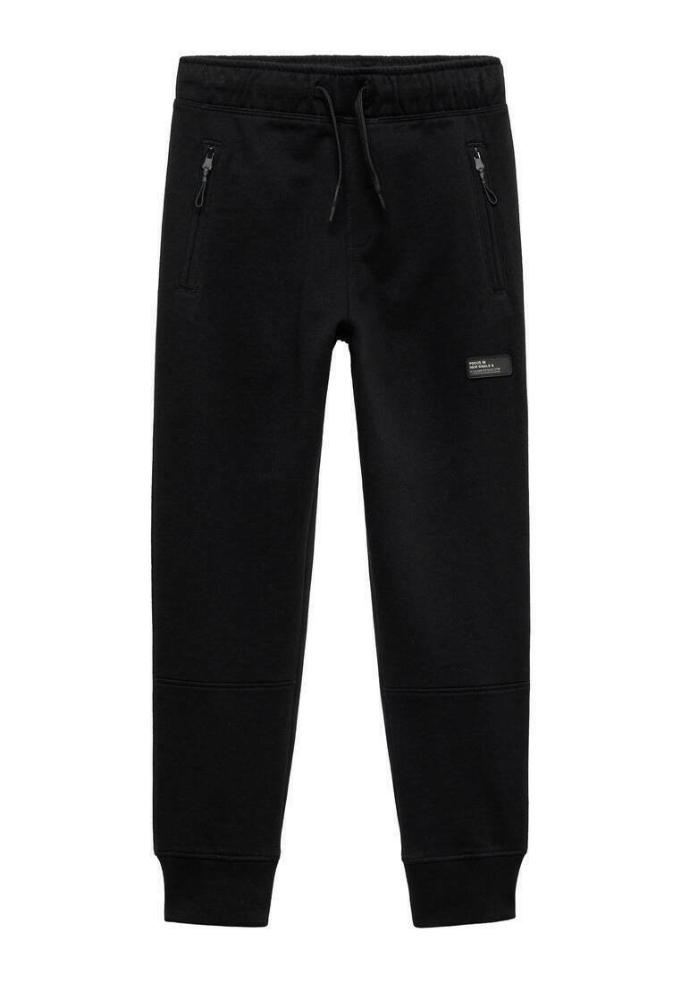 Crne trenirke s pojasom na vezivanje, dva bočna džepa sa patentnim zatvaračem, suženi nogavici i rebrastim manžetama. Izrađene od mekanog, materijala sličnog flisu.