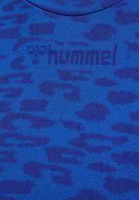 Blå textil med struktur och ett subtilt leopardmönster samt "hummel"-logotypen präglad i mörkare blått. Slät stickad yta.