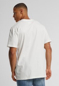 Camisa blanca de manga corta con un ajuste relajado. Hecha de algodón suave, presenta un escote redondo y una textura lisa.