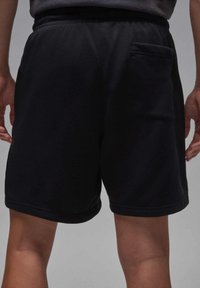 Zwarte sportshorts met een zachte textuur, elastische tailleband en een enkel achterzakje voor gemak.