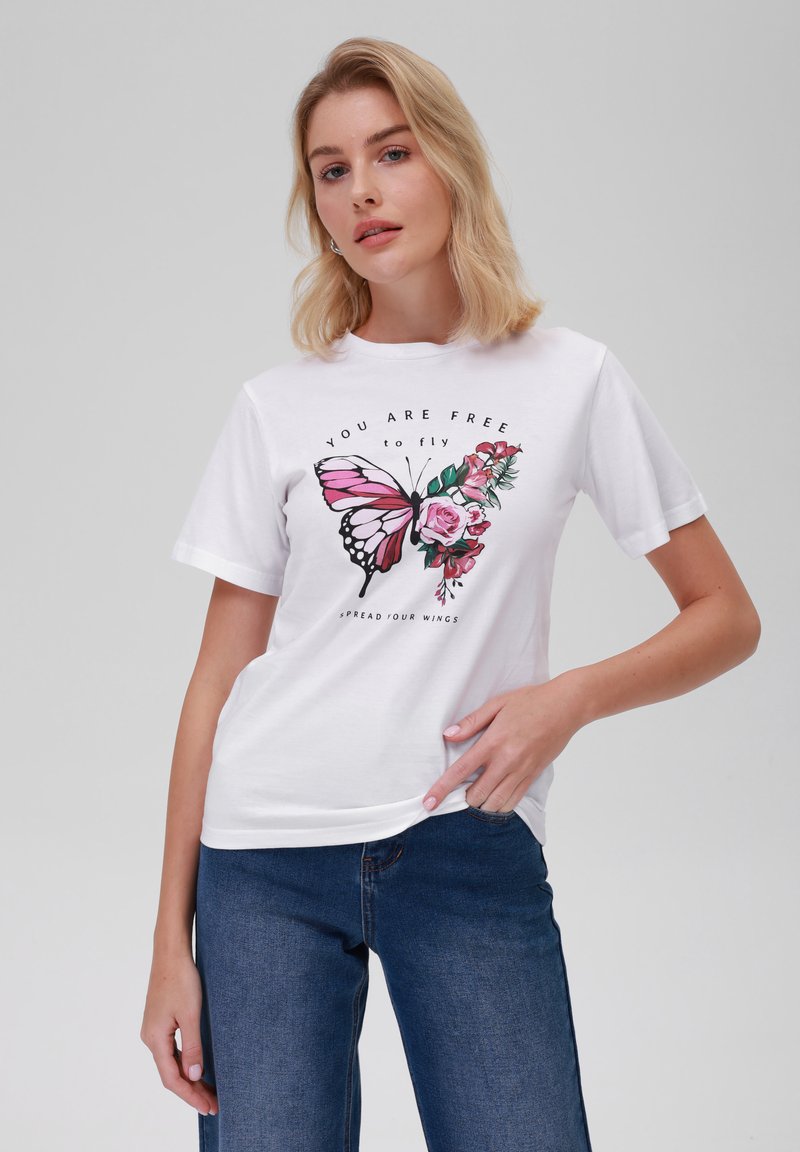 Bílý bavlněný tričko s velkým potiskem růžové motýla a růží, s textem "JSI VOLNÝ, abys létal" v černém písmu.