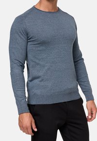 Blauer Strickpullover mit langen Ärmeln, Rundhalsausschnitt und gerippten Bündchen und Saum. Der Stoff wirkt glatt und hat eine mittlere Dicke.