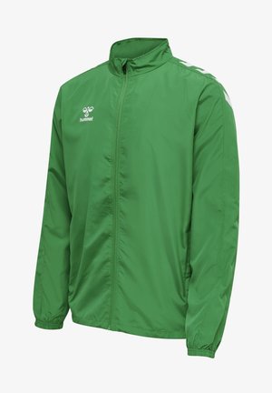 Grøn letvægtsjakke lavet af glat polyester, med høj krave, fuld lynlås og kontrastfulde hvide sidelister.