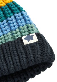 Strikket hue med livlige striber i teal, blå, grøn og gul. Mørk ribbet manchet med et cremefarvet mærke og en blå stjerneaccents.