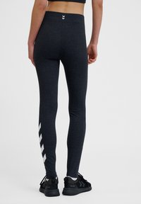 Ciemnoszare legginsy wykonane z elastycznego materiału, z wysokim stanem i białym wzorem w zygzak na dolnej części.