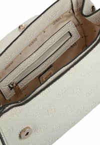 Borsa bianca texturizzata con motivo floreale in rilievo, fodera interna beige con logo "GUESS" e tasca con zip dotata di tirante in metallo.