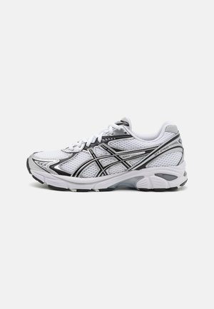 Chaussure de course blanche et noire avec empeigne en mesh, semelle amortissante et bandes noires de la marque sur le côté portant l’étiquette GT-2160.