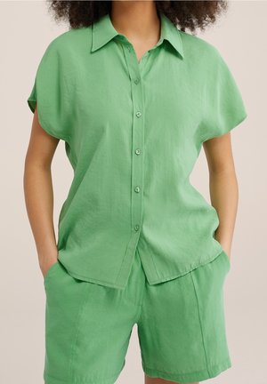 Groene linnen korte mouwen shirt met een knoopsluiting aan de voorkant, met een relaxte pasvorm, kraag en lichte glans, gecombineerd met bijpassende groene shorts.