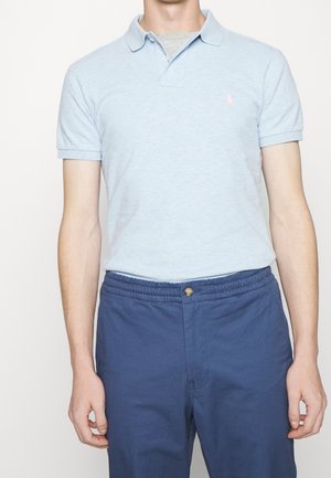 Helles blaues Poloshirt mit kurzen Ärmeln, mit einem kleinen gestickten Logo auf der Brust. Kombiniert mit navyblauen Hosen mit elastischem Bund.