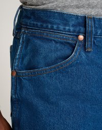 Sinine teksariie, lähedane vaade taskule, millel on vaskne riistvara, oranž õmblus ja sile tekstuur.