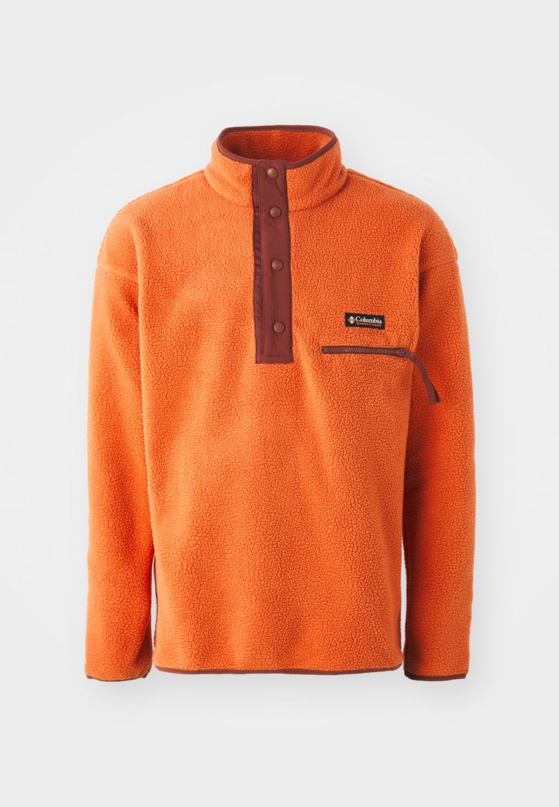 Pullover in pile arancione con colletto alto, patta con bottoni marroni e tasca con zip sul petto. Tessuto morbido con vestibilità relaxed.