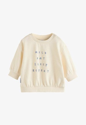 Krémový sveter s okrúhlym výstrihom a elastickým lemom. Obsahuje modrý text: "MIESTO JEDLO SPÁNOK OPAKOVAŤ." Puff rukávy. Bavlnený materiál.