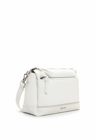 Biała skórzana torebka o fakturowanej powierzchni. Posiada zamknięcie na zamek, regulowany pasek oraz przednią kieszeń na zamek. Kwadratowy kształt.
